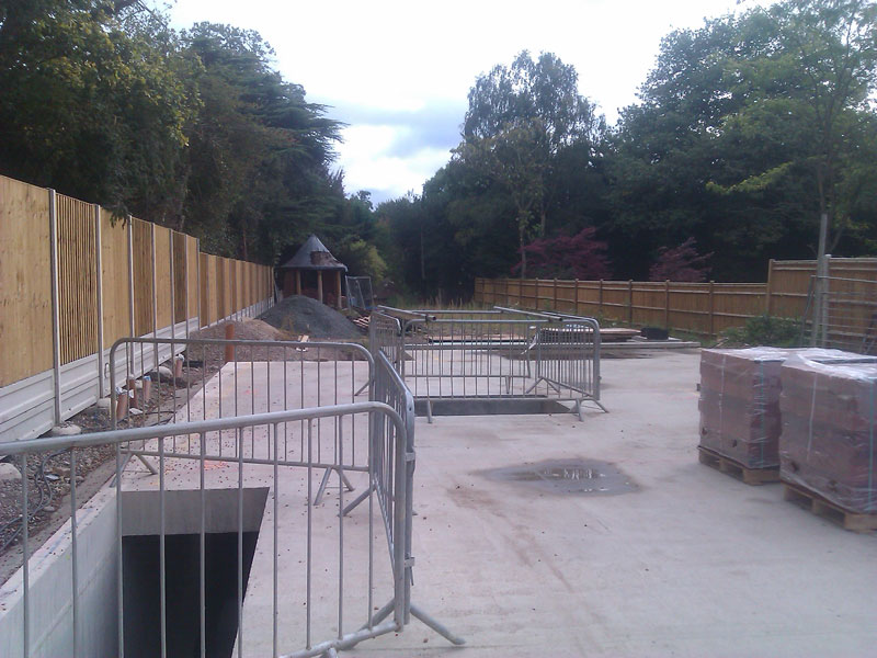 Groundworks stage with a concrete slab, site fencing and stacked materials