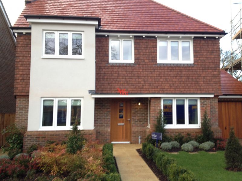 New home with a tiled roof, brick and render finish and a landscaped front garden