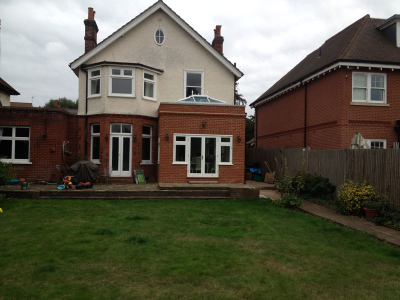 Garden view of a completed red-brick extension with white doors and a roof lantern