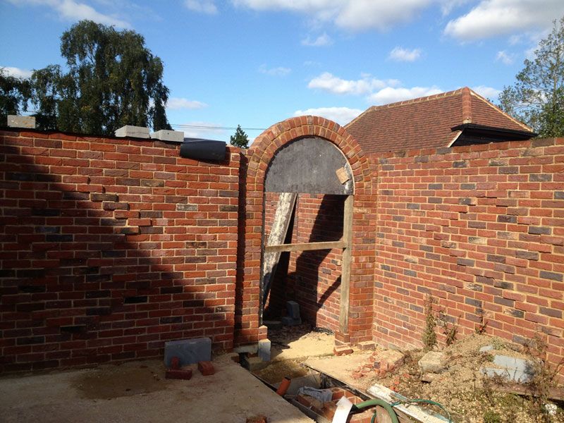 Brick garden walls with an arched doorway under construction