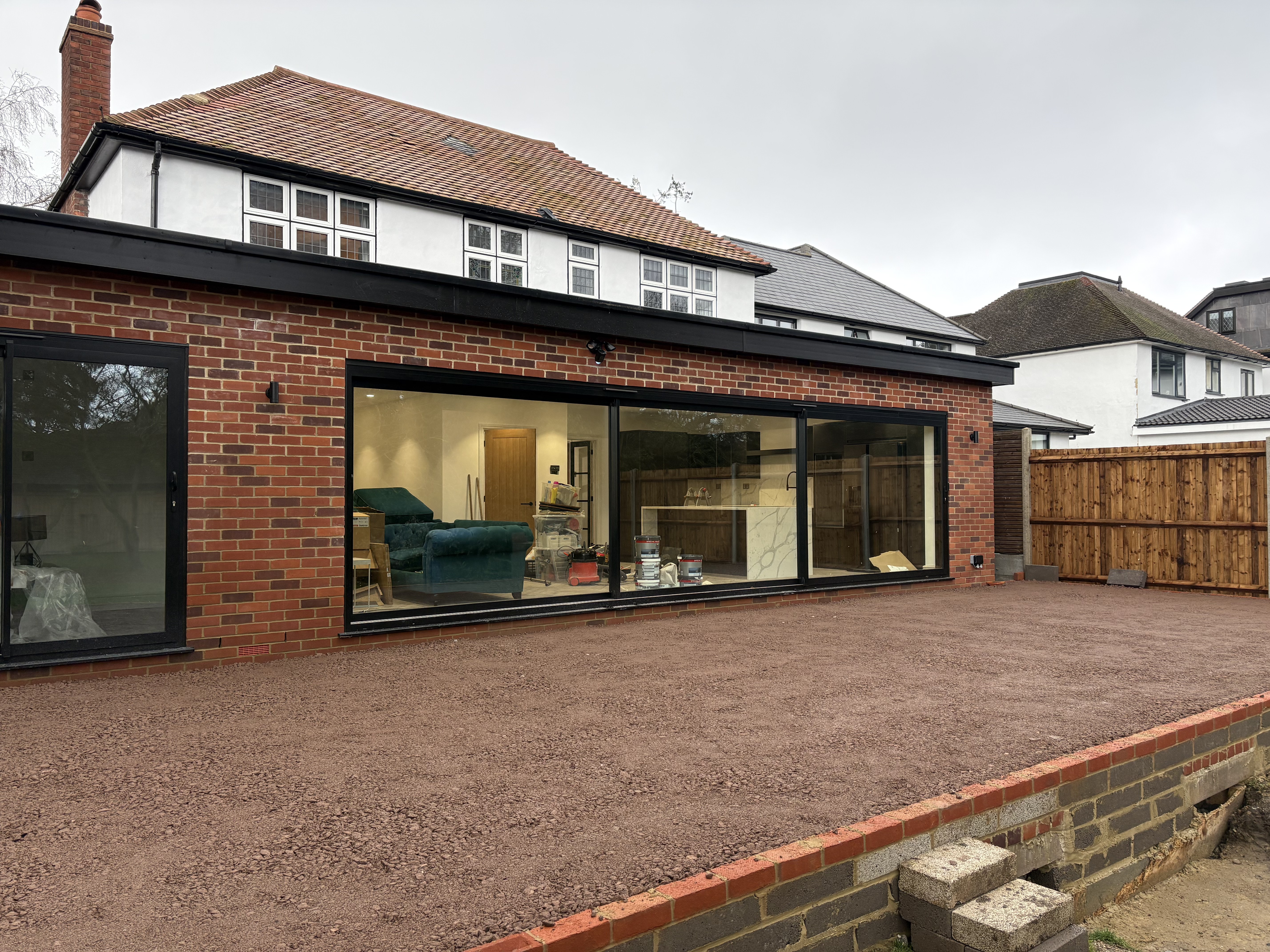 Red-brick rear extension with full-width black sliding doors and a white-rendered first floor above