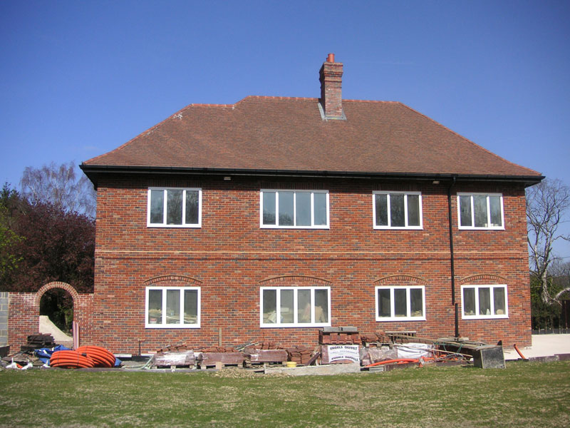 Completed two-storey red-brick house in Westerham with a hipped tiled roof, chimney and white windows