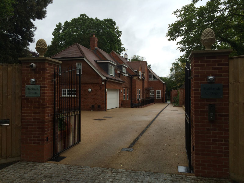 Timber-clad cottage homes behind brick gate pillars and black gates