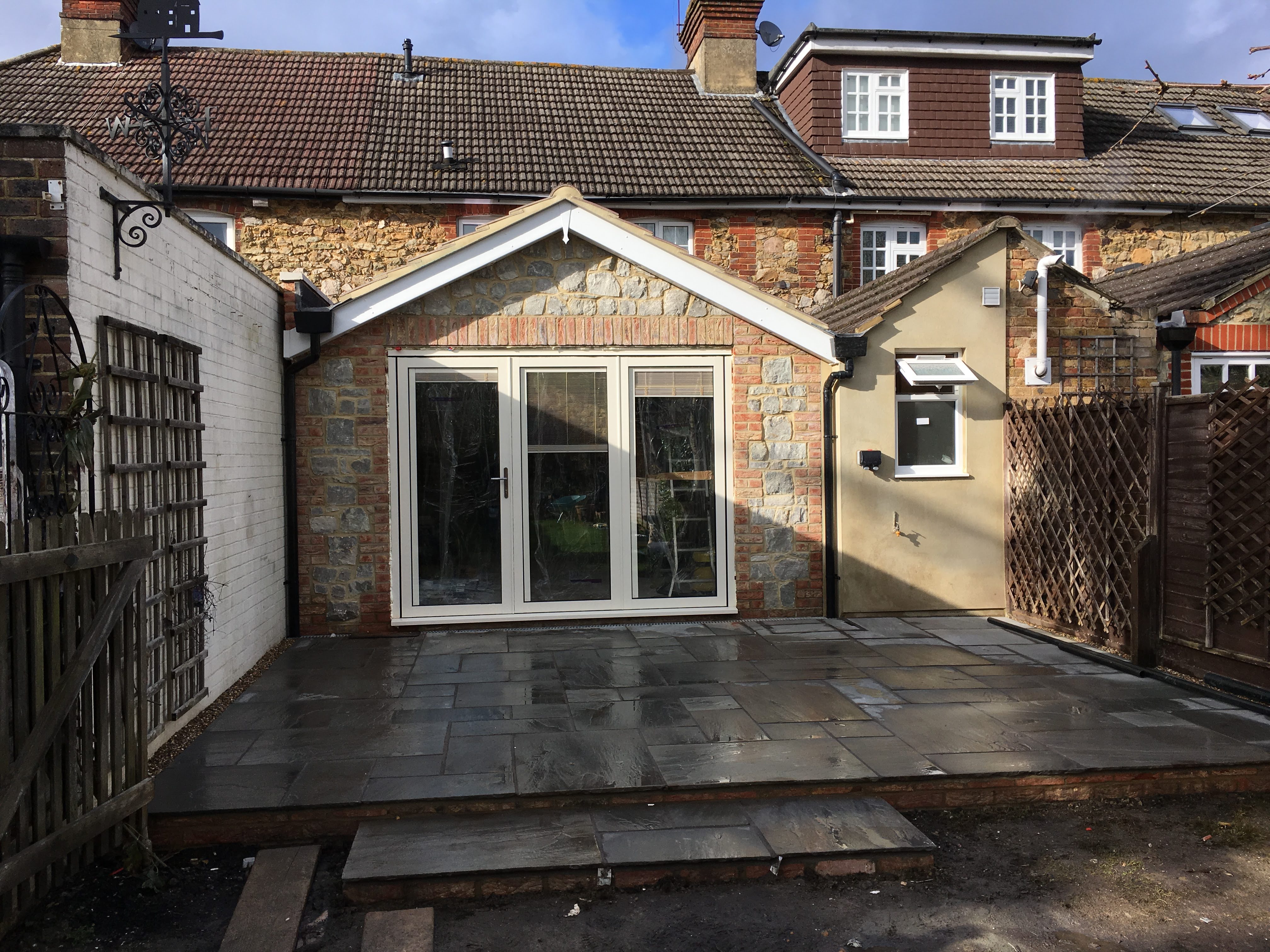 Kemsing, Sevenoaks: stone and brick gabled rear extension with cream French doors opening onto a flagstone patio