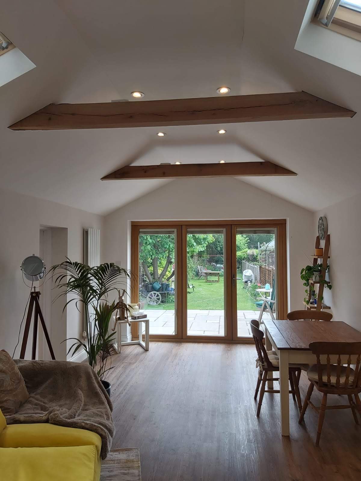 Extension interior with a vaulted ceiling, oak beams, rooflights and glazed doors opening onto a garden