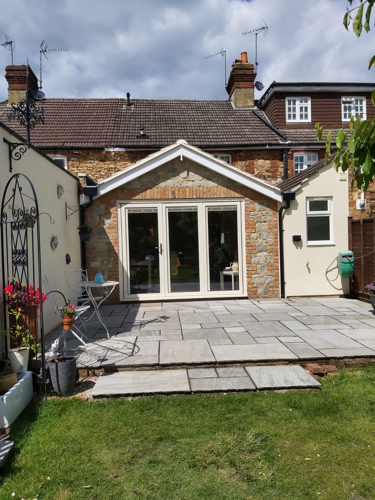 Stone-faced extension with white glazed doors opening onto a patio