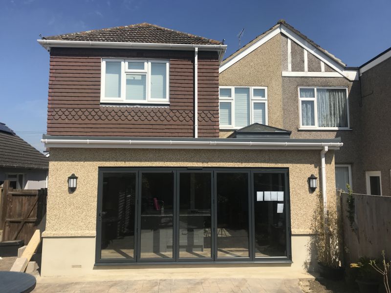 Completed rear extension with rendered walls, grey bifold doors and a tiled roof