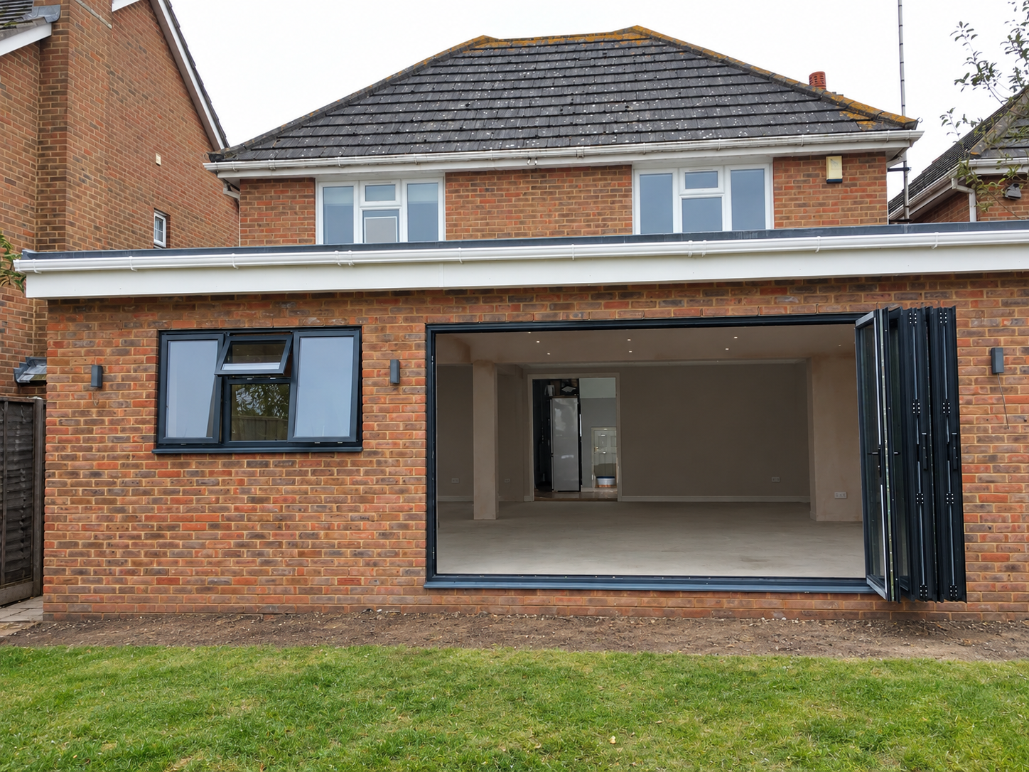 Barnfield Rd: red-brick single-storey rear extension with anthracite bifold doors opening onto a lawn