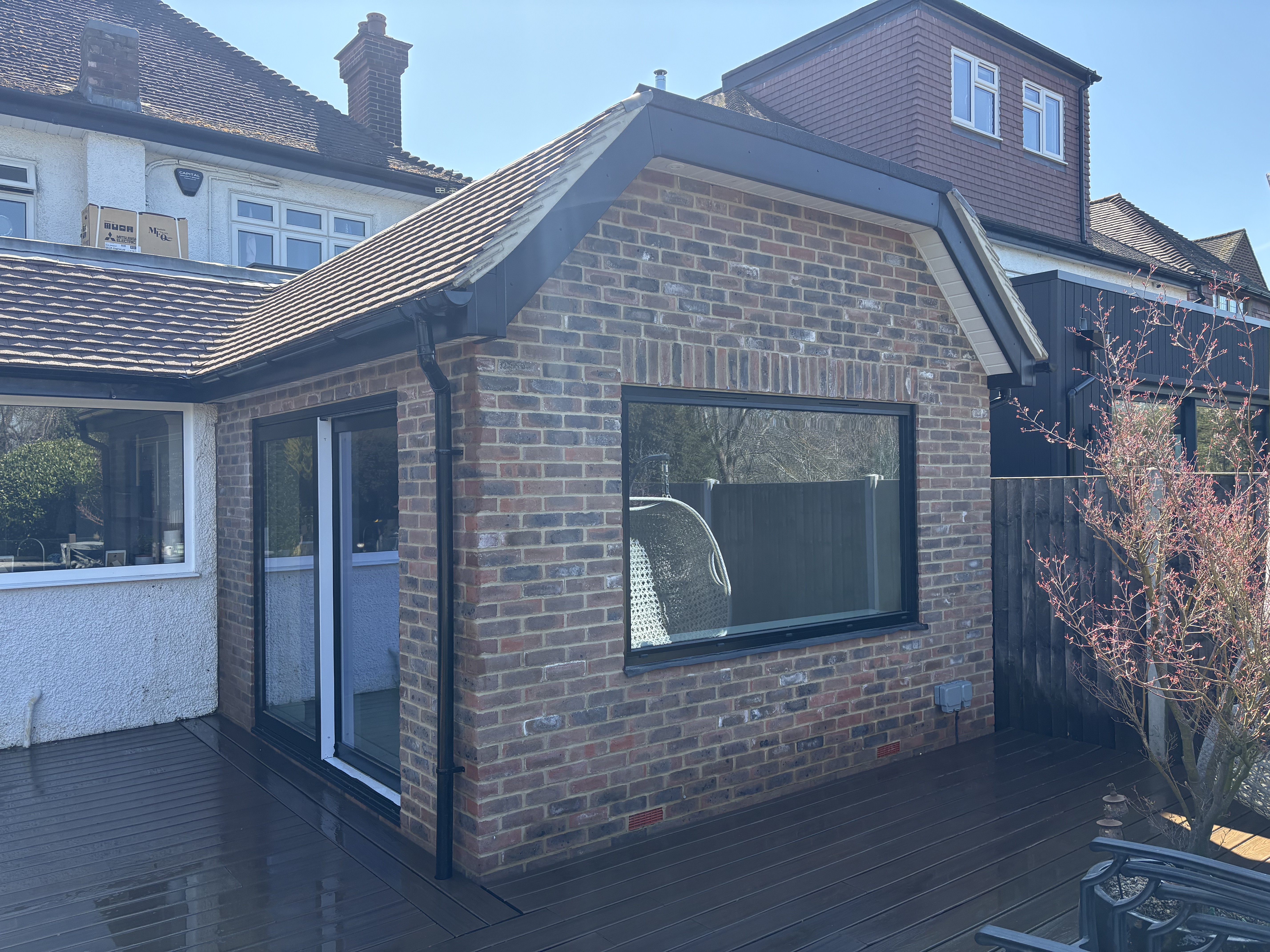 Wansunt Rd, Bexley: red-brick rear extension with a black-framed picture window and sliding doors beside timber decking