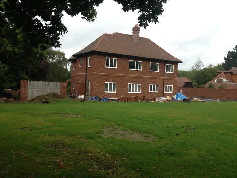 Two-storey brick house under construction beside a large lawn