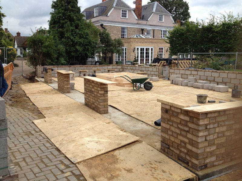 Brick piers and low garden walls under construction on a paved landscaping project