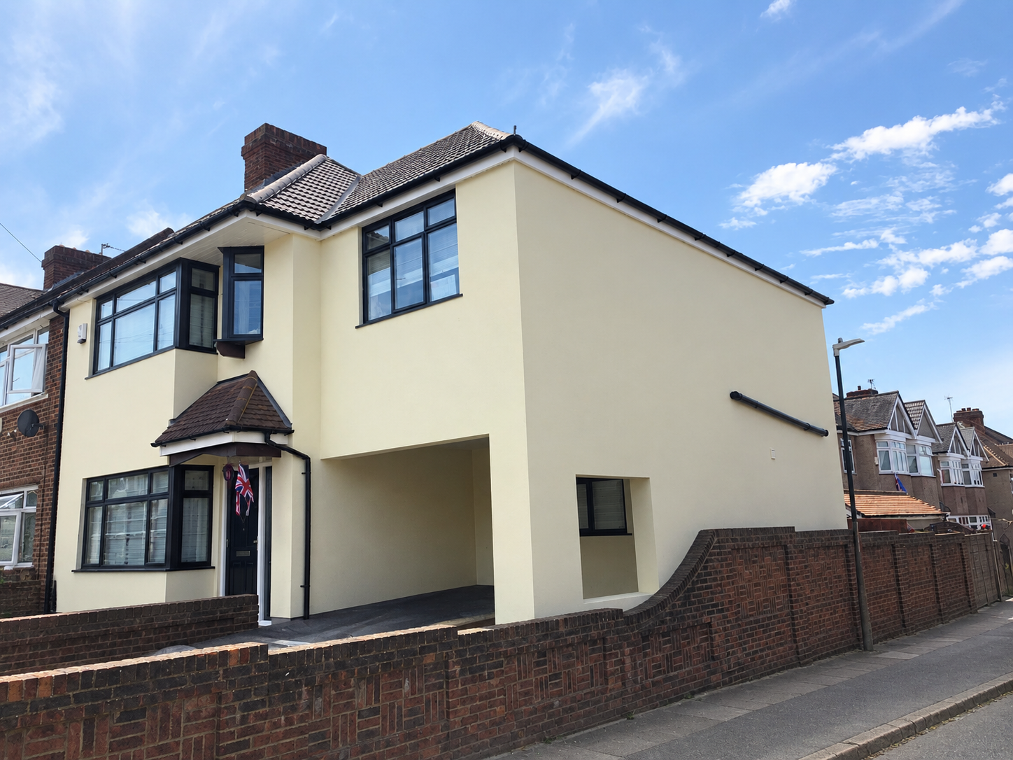 West Hill Rd, Dartford: cream-rendered two-storey extension with black-framed windows behind a low brick wall