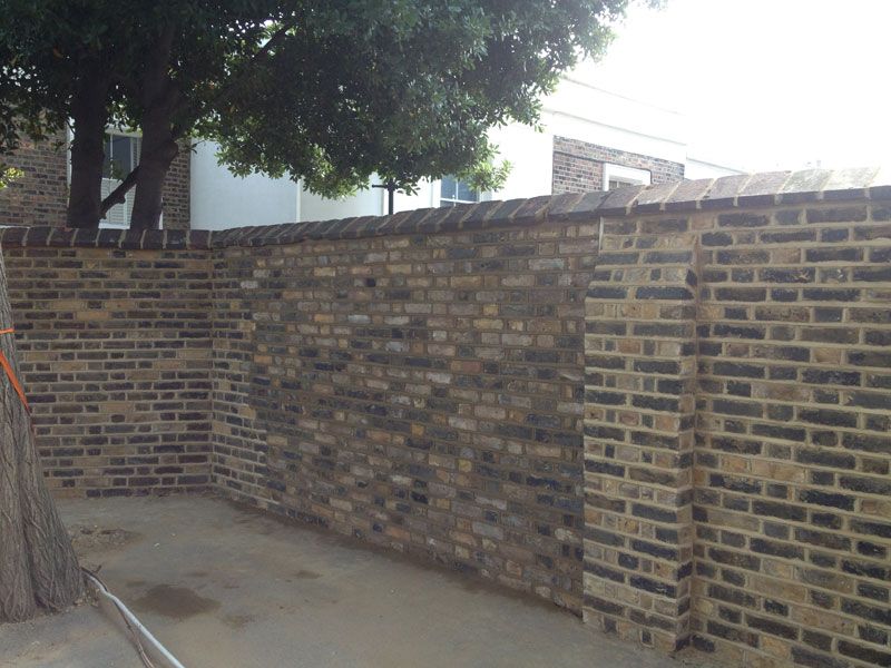 Finished reclaimed-brick garden wall with brick piers and curved capping
