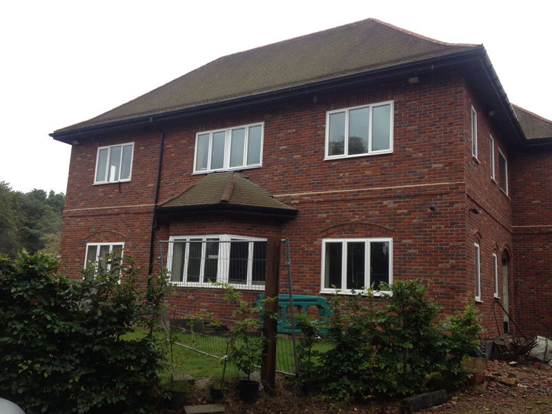 Two-storey red-brick home with white windows during final site work